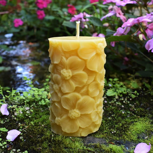 Yellow beeswax pillar covered in large raised flowers beside a garden stream.