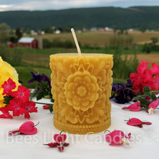 Golden floral beeswax pillar with a large raised blossom and ornamental leaves.