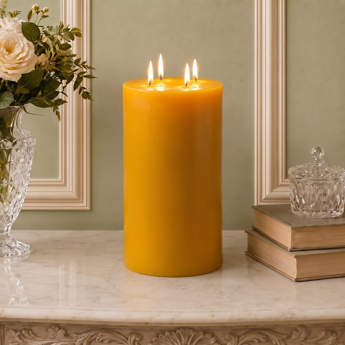 Extra-tall golden four-wick beeswax pillar displayed beside flowers and books.