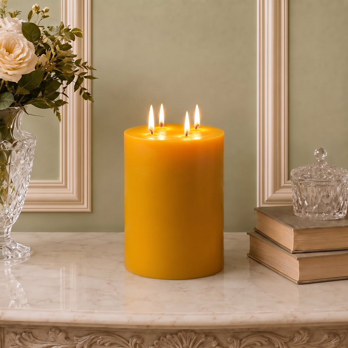 Golden multiwick beeswax pillar burning on a pale surface beneath decorative wall molding.